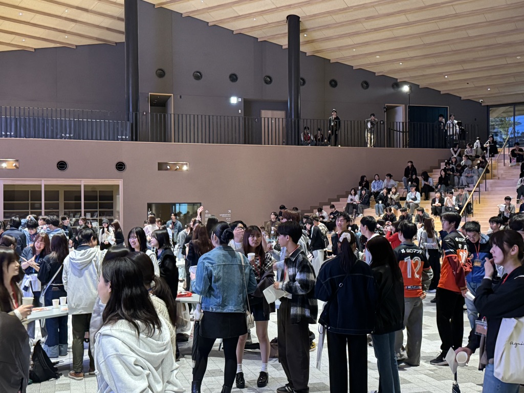 会場のテーブル付近や階段に集まり交流する参加者たち