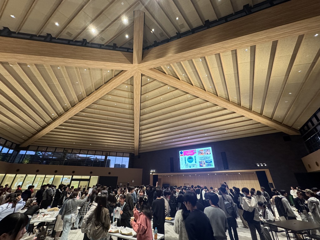 夕方の会場で、テーブルごとに話を聞いたり交流したりする学生たち